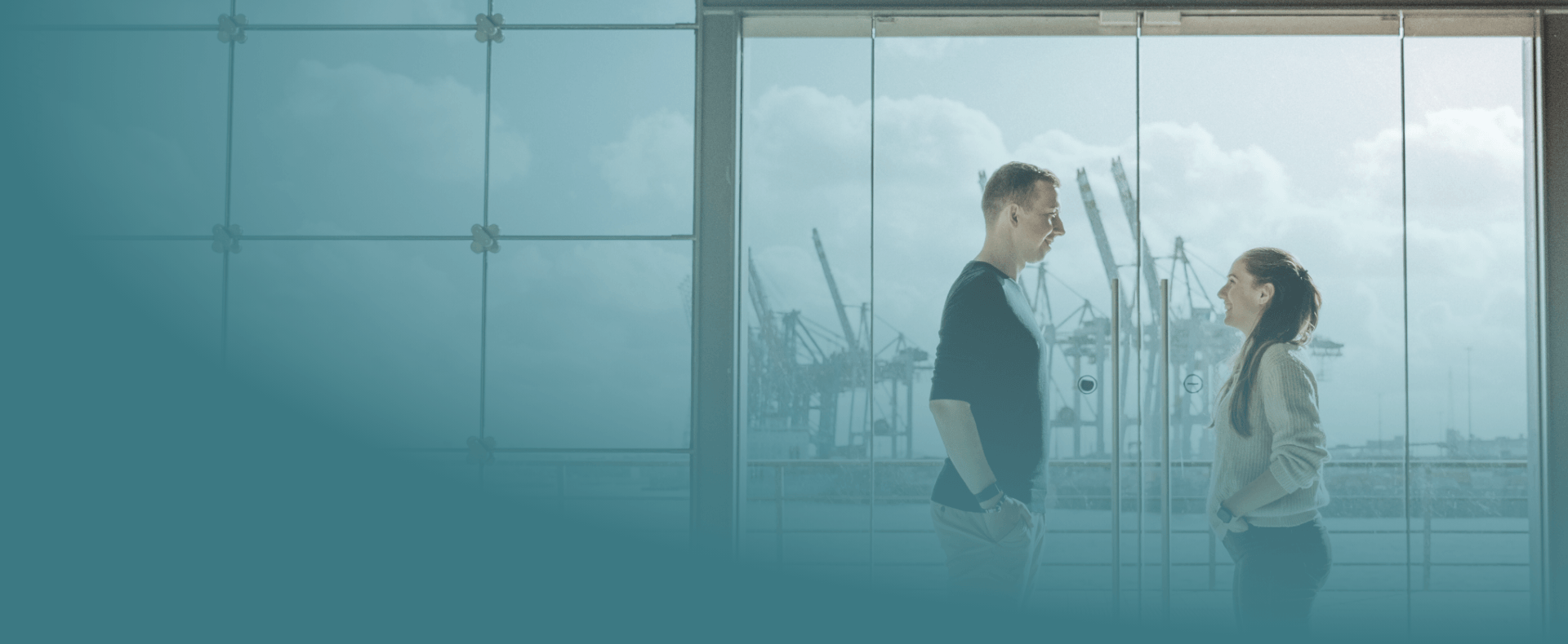 Yase und Lukas schauen sich gegenseitig an. Im Hintergrund die Kräne des Hamburger Hafens.