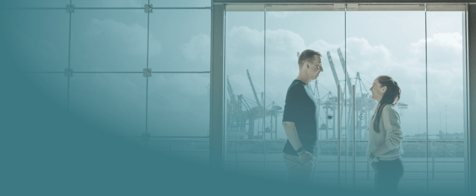 Yase und Lukas schauen sich gegenseitig an. Im Hintergrund die Kräne des Hamburger Hafens.