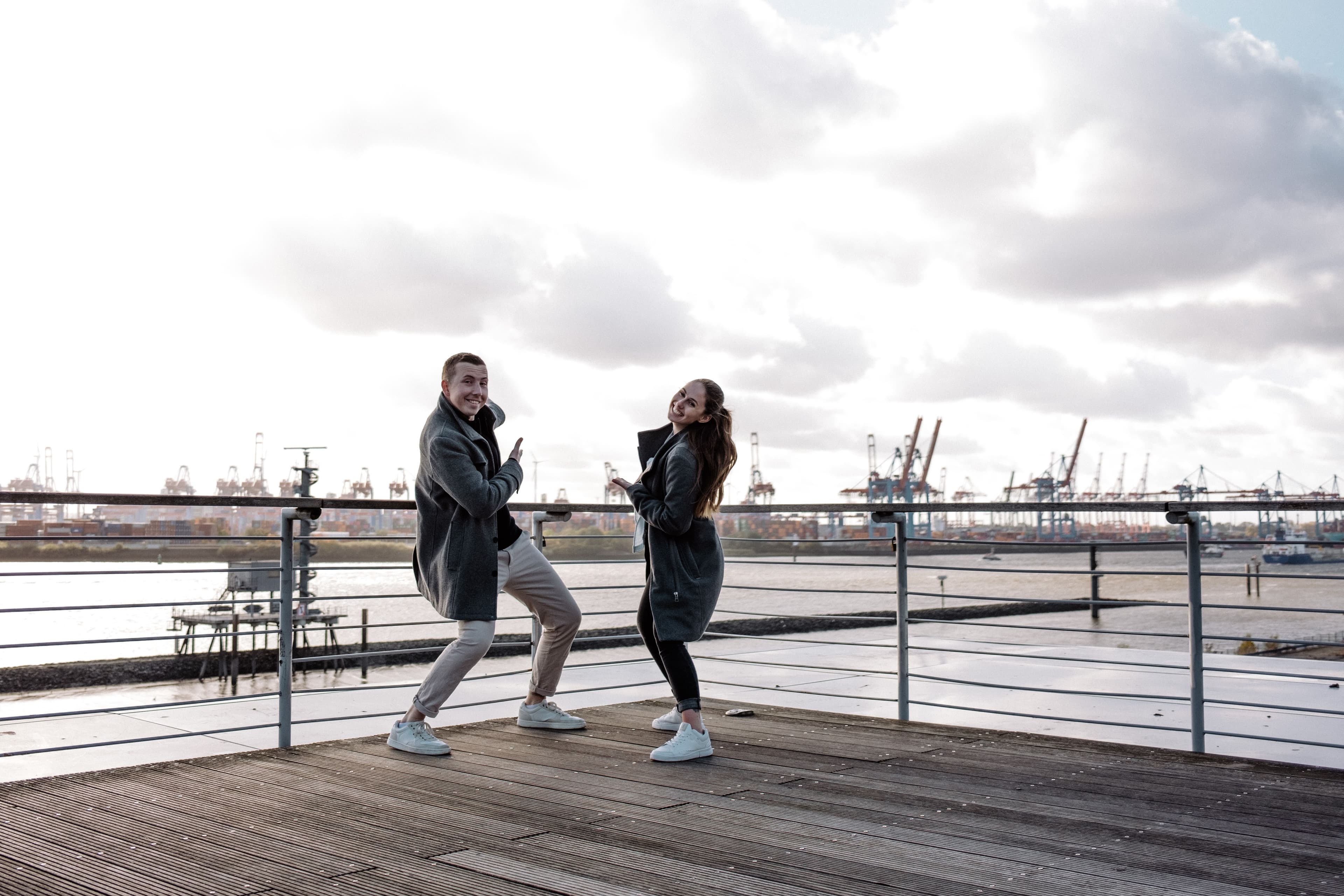 Yase und Lukas machen Grimassen und zeigen auf den Hafen.