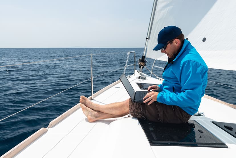 Ein Mann mit Laptop am Bug eines Segelboots